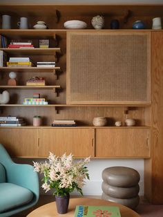 a living room with two blue chairs and a coffee table in front of a book shelf