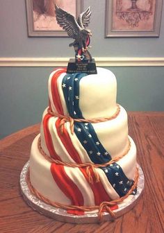 a three tiered cake with an eagle on top and american flag ribbons around it