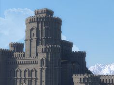 a very large castle like structure with mountains in the backgroung and blue sky