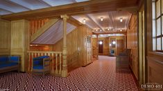 the interior of a wooden house with red and blue carpeting on the floor, stairs leading up to the second floor