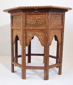 a wooden table with carvings on the top and bottom, sitting against a white background