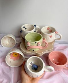 a hand is holding several cups and saucers