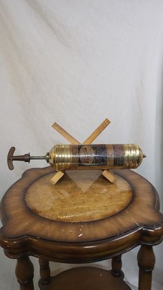 a wooden table topped with a metal object on top of it's side stand