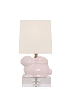 a lamp that is on top of a glass block with a white shade over it