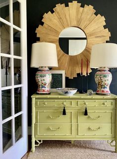 a green dresser with two lamps and a mirror