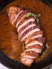 pork roast in a cast iron skillet with garnishes on the side