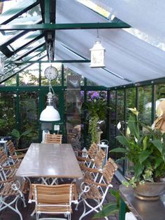 an outdoor dining area with tables, chairs and potted plants in the middle of it