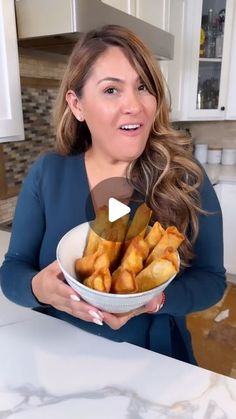 a woman holding a bowl full of french fries in her hands and talking to the camera