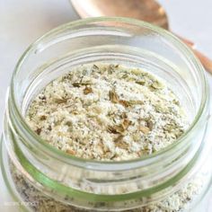 a glass jar filled with food sitting on top of a table next to a wooden spoon