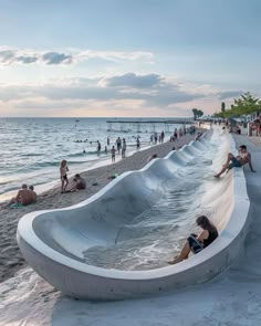 people are sitting on the beach next to an upside down water slide