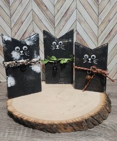 three black cats made out of wood sitting on top of a wooden table next to each other