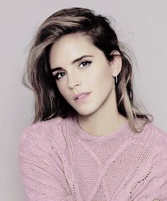 a woman in a pink sweater is posing for the camera