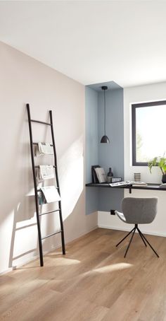 an empty room with a ladder leaning against the wall next to a desk and chair