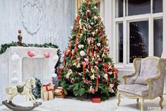 a decorated christmas tree sitting in front of a fire place next to a rocking chair