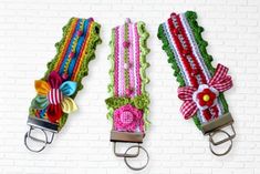 three colorful crocheted belts with bows and ribbons on them are hanging from hooks