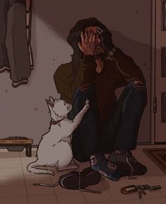 a man sitting on the floor next to a white cat with his head in his hands