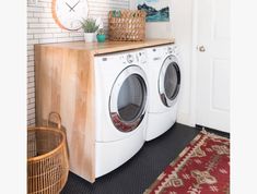 a washer and dryer sitting in a room next to a door with a clock on the wall