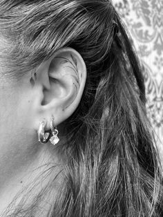 black and white photograph of woman's ear with piercings on her left side