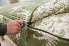 someone is opening the zipper on a green and white comforter