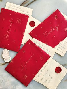 three red envelopes with writing on them and some wax stampers next to them