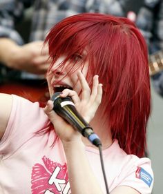 a woman with red hair singing into a microphone