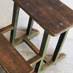 an old wooden table and two stools sitting on the floor in front of a white wall