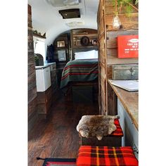 the interior of an rv with wood flooring and walls, including a kitchen area