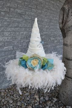 a white hat with feathers on it sitting next to a stone wall and a tree