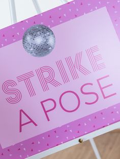 a pink sign that says strike like a pose with a disco ball on it