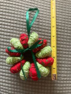 an ornament made out of fabric with green ribbon and red flowers on it