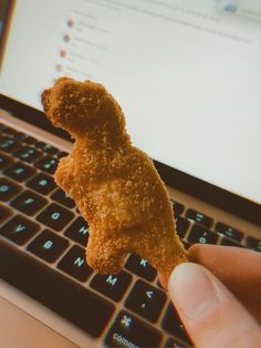 a person is holding a small piece of food in front of a laptop computer keyboard