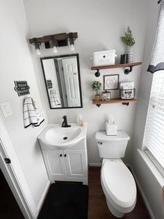 a bathroom with a toilet, sink and shelves on the wall next to the window