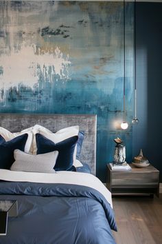 a bed with blue and white pillows on top of it next to a night stand