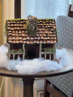 a doll house on top of a table covered in snow