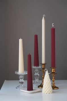 three candles, one white and one red are sitting on a table