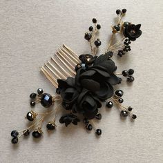 a hair comb with black flowers and pearls on it's side, sitting on a table