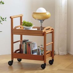 a wooden serving cart with two bowls on it and a lamp in the corner next to it