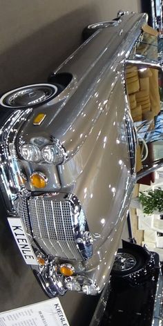 the front end of a silver car on display