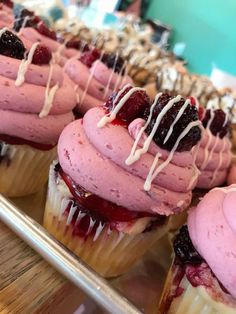 cupcakes with pink frosting and cranberry toppings sitting on a tray