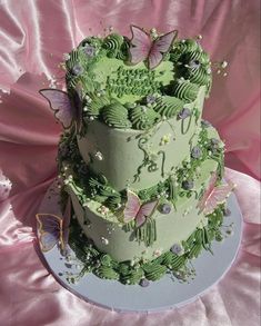 a three tiered cake with green frosting and butterflies