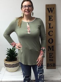 This basic olive green pullover has just enough flare. The cuffs and neckline have a little floral design on an ivory background. Has 5 wooden buttons if you want to show a little more skin or have a v-neck. Fit: It is a fitted top, if you want a looser fit go up one size. Model is wearing a large, typically a medium. Olive Green Top, Green Pullover, Ivory Background, Fitted Top, Wooden Buttons, Green Top, Go Up, Green Tops, Olive Green