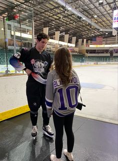 two people standing in an indoor hockey rink