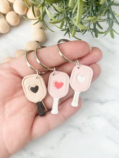 three keychains in the shape of heart shaped keys, one with two hearts on it