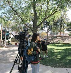 a woman standing in front of a camera on a sidewalk