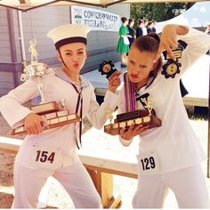 two women in white uniforms holding trophies and posing for the camera