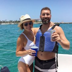 a man and woman on a boat posing for the camera with drinks in their hands