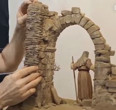 a man is making a statue out of clay and stone blocks with his hands on the base