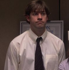 a man and woman standing next to each other in front of a poster on the wall