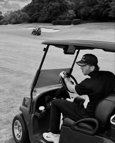 a man driving a golf cart on a grass covered field