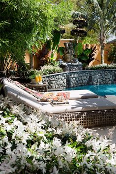 an outdoor pool with wicker furniture and plants